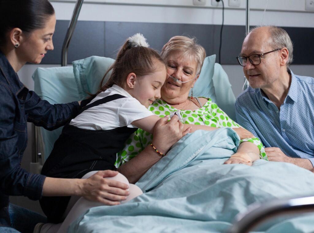 A young girl hugging a palliative patient while family looks on
