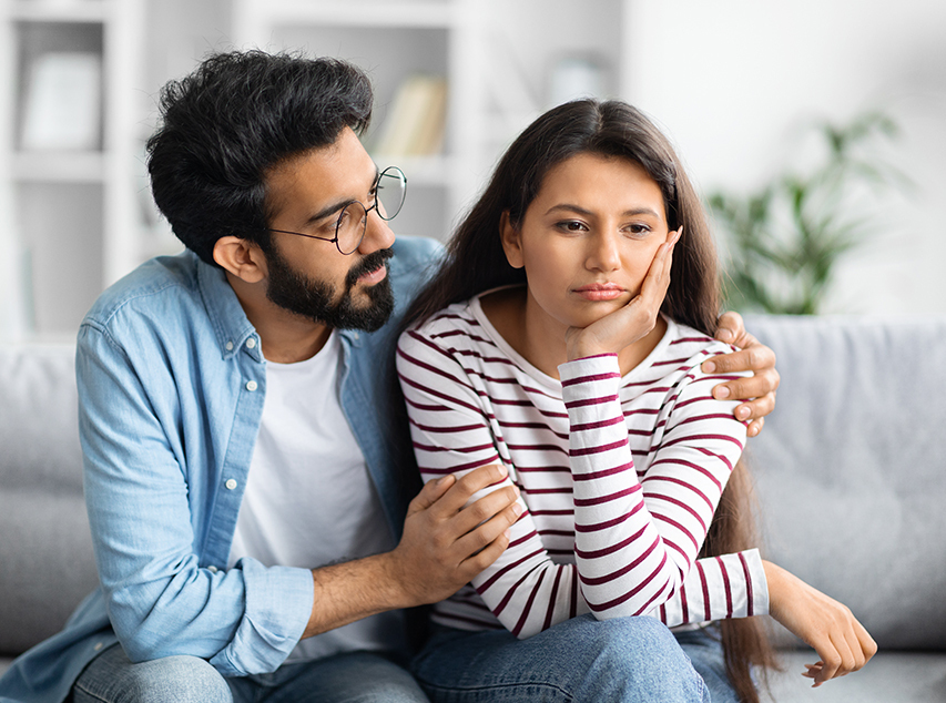 A man with a beard and glasses comforting a woman