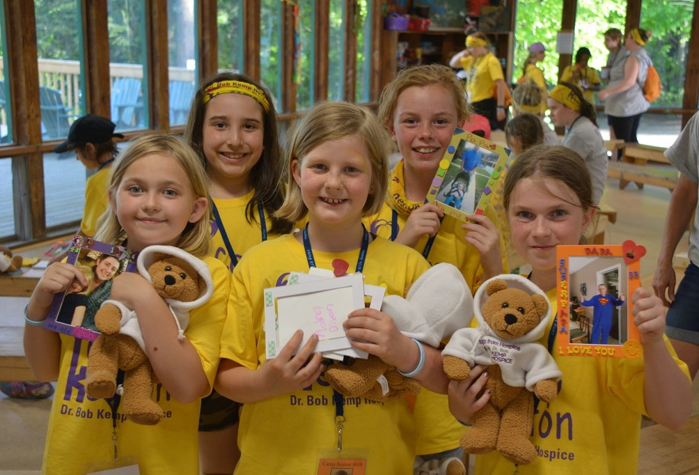 A group of young campers wearing camp shirts and holding keepsakes from home